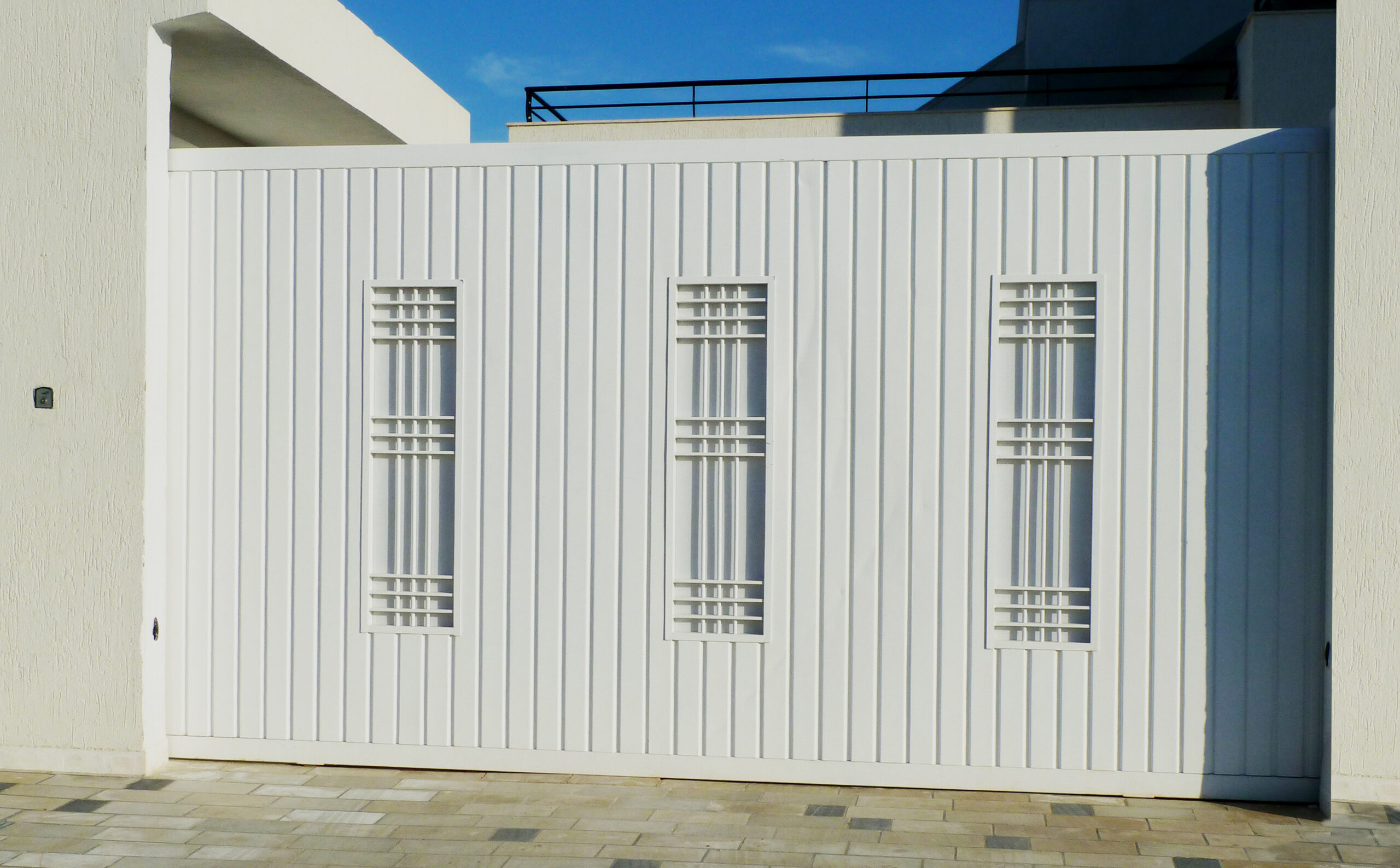 1Porte coulissante en tôle nervurée simple paroi décorée avec des panneaux en fer forgé habillés en tôle simple. Porte coulissante en tôle nervurée simple paroi décorée avec des panneaux en fer forgé habillés en tôle simple.