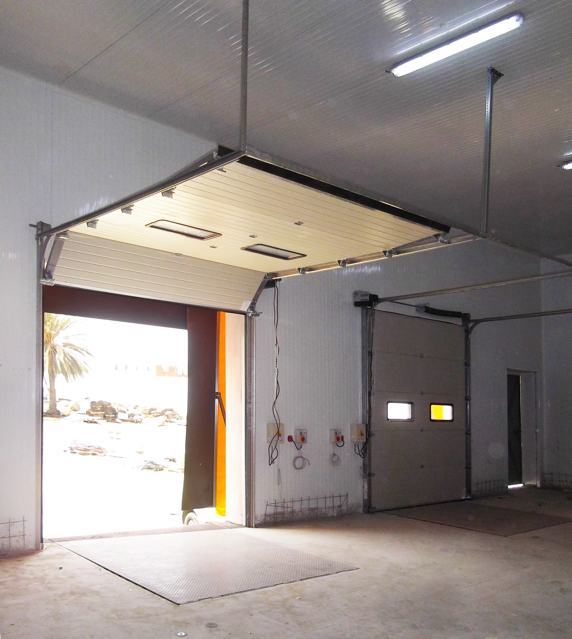 Porte sectionnelle industrielle avec hublots couleur blanche.