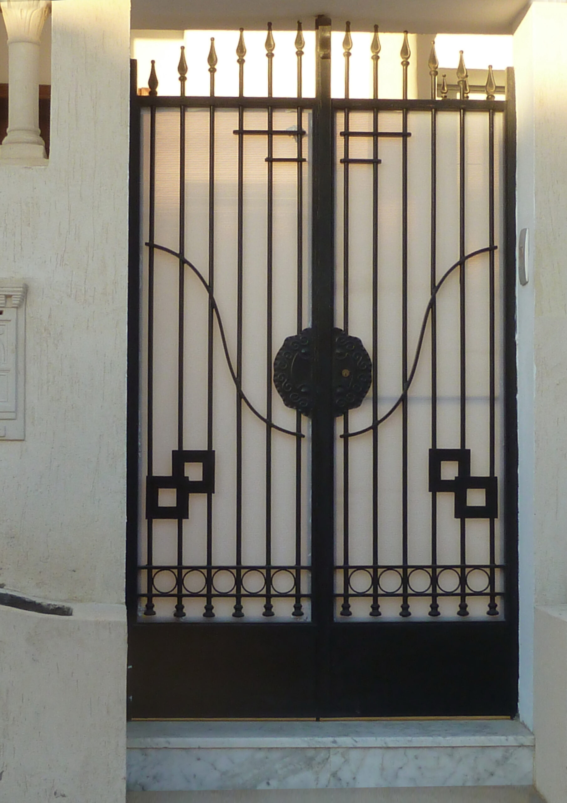 Porte battante à deux vantaux en fer forgé avec serrure électrique.