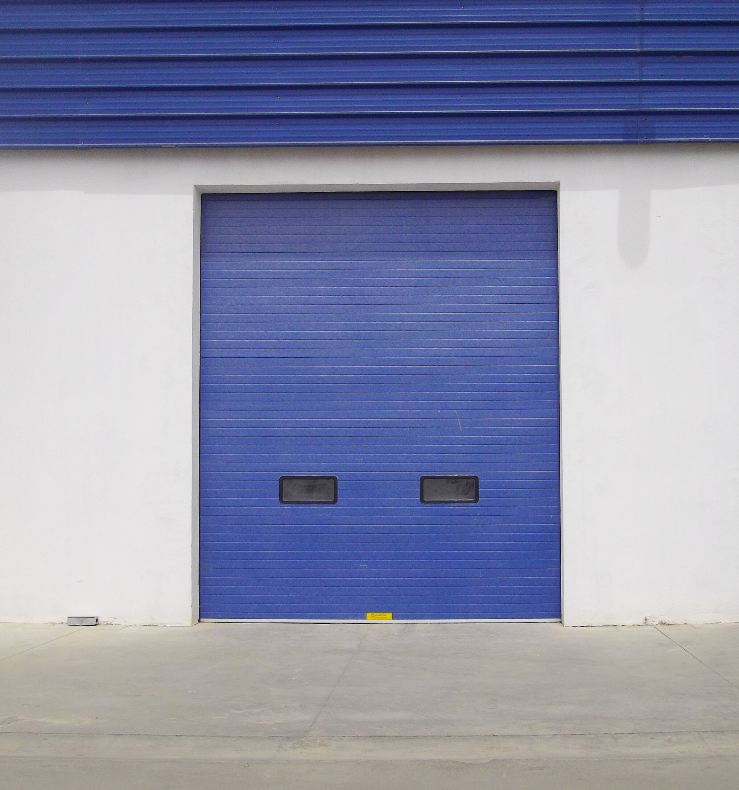 Porte sectionnelle industrielle avec hublots couleur bleu.