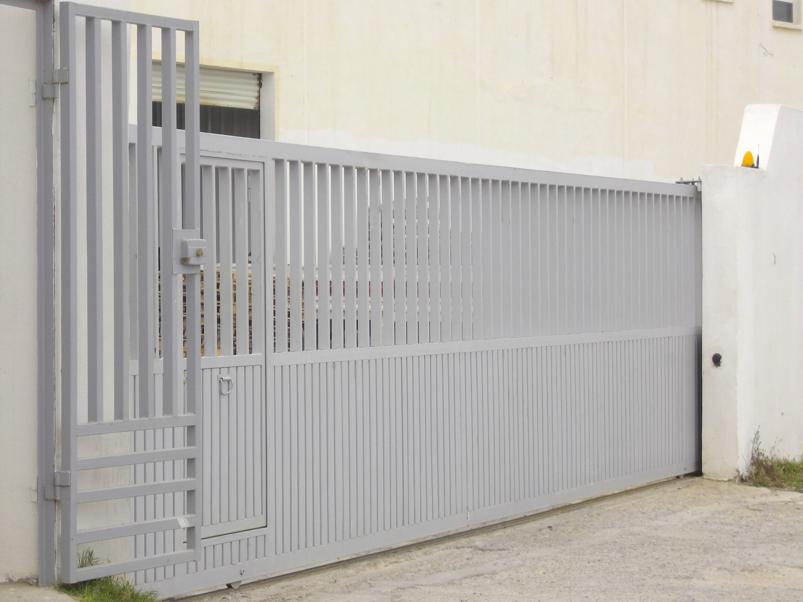 2Porte coulissante motorisée avec portillon intégré en tôle nervurée simple paroi avec barreaudage. Porte coulissante motorisée avec portillon intégré en tôle nervurée simple paroi avec barreaudage.