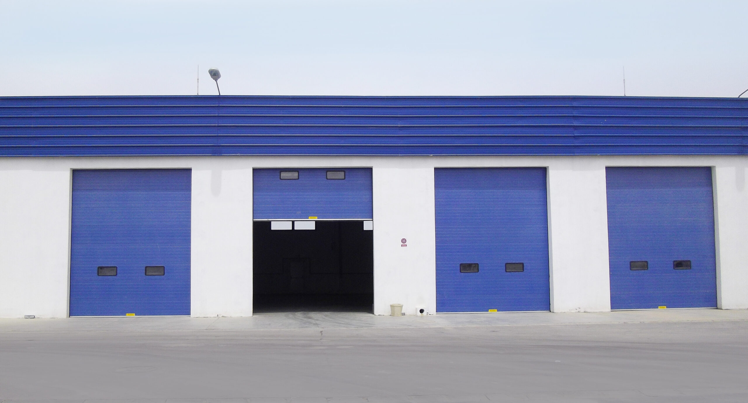 Portes sectionnelles industrielles avec hublots couleur bleu.