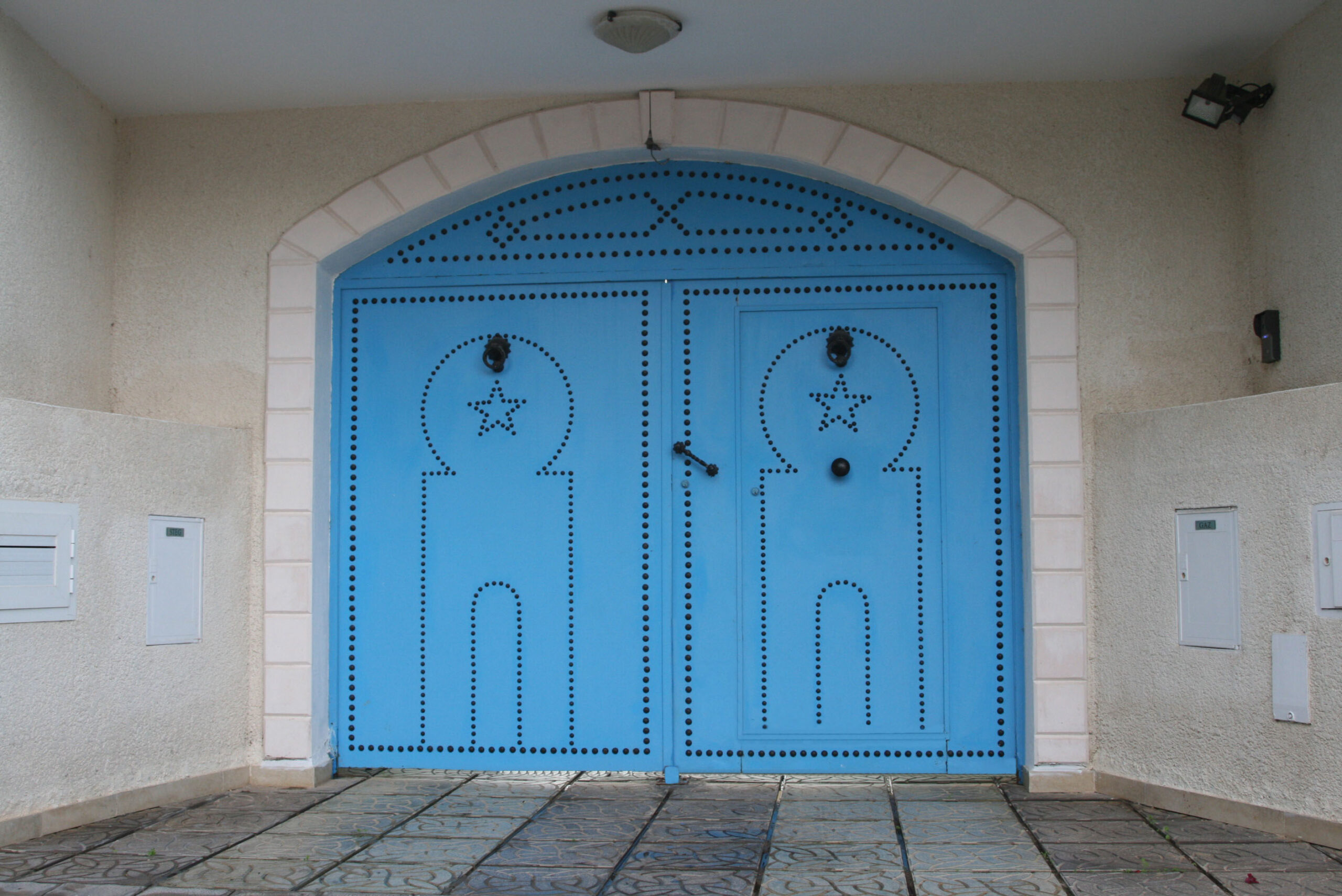 Porte battante à deux vantaux avec portillon intégré motif sidi bou said tôle pleine clouée. Porte battante à deux vantaux avec portillon intégré motif sidi bou said tôle pleine clouée.