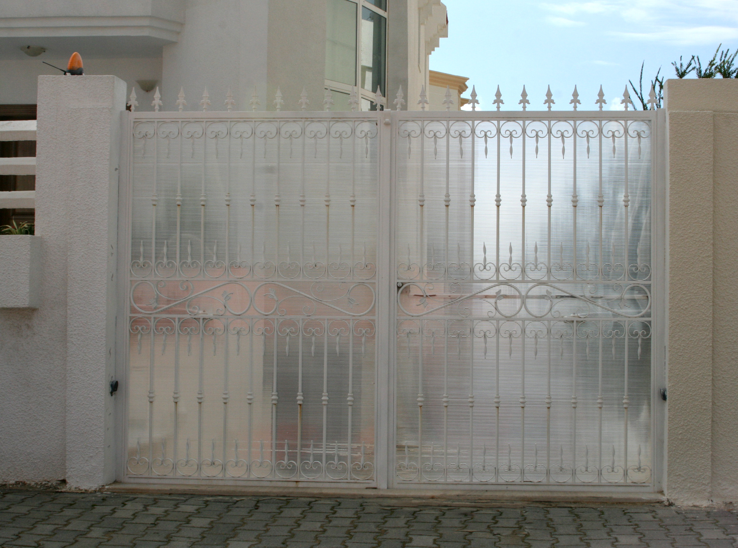 Porte battante à deux vantaux en fer forgé motorisée bras articulés habillage polycarbonate. Porte battante à deux vantaux en fer forgé motorisée bras articulés habillage polycarbonate.