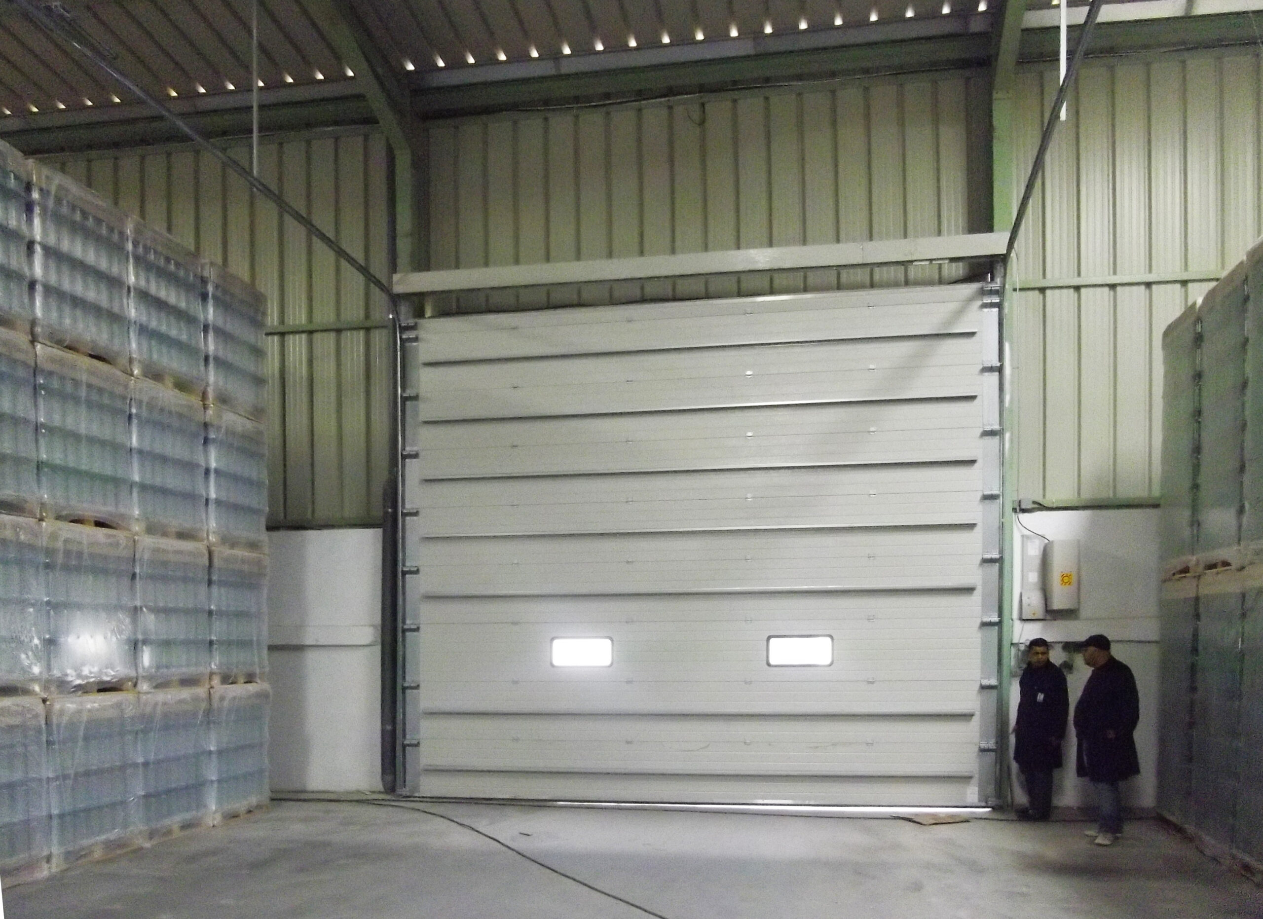 Porte sectionnelle industrielle avec hublots couleur blanche.