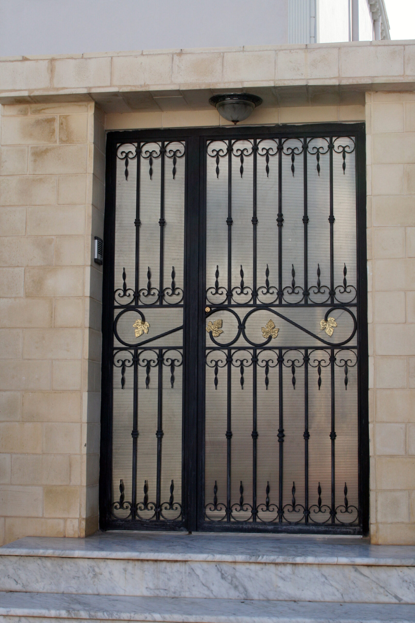 9 Porte d’entrée battante en fer forgé deux vantaux partie fixe et partie mobile habillage en polycarbonate.