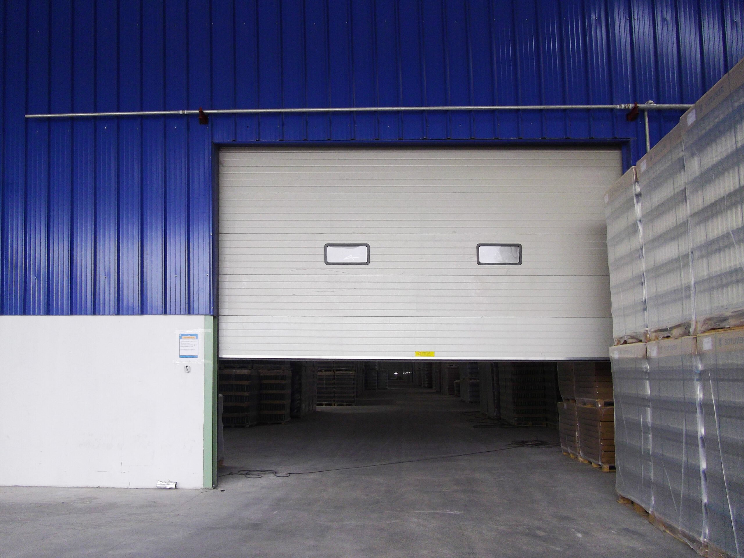 Porte sectionnelle industrielle avec hublots couleur blanche.