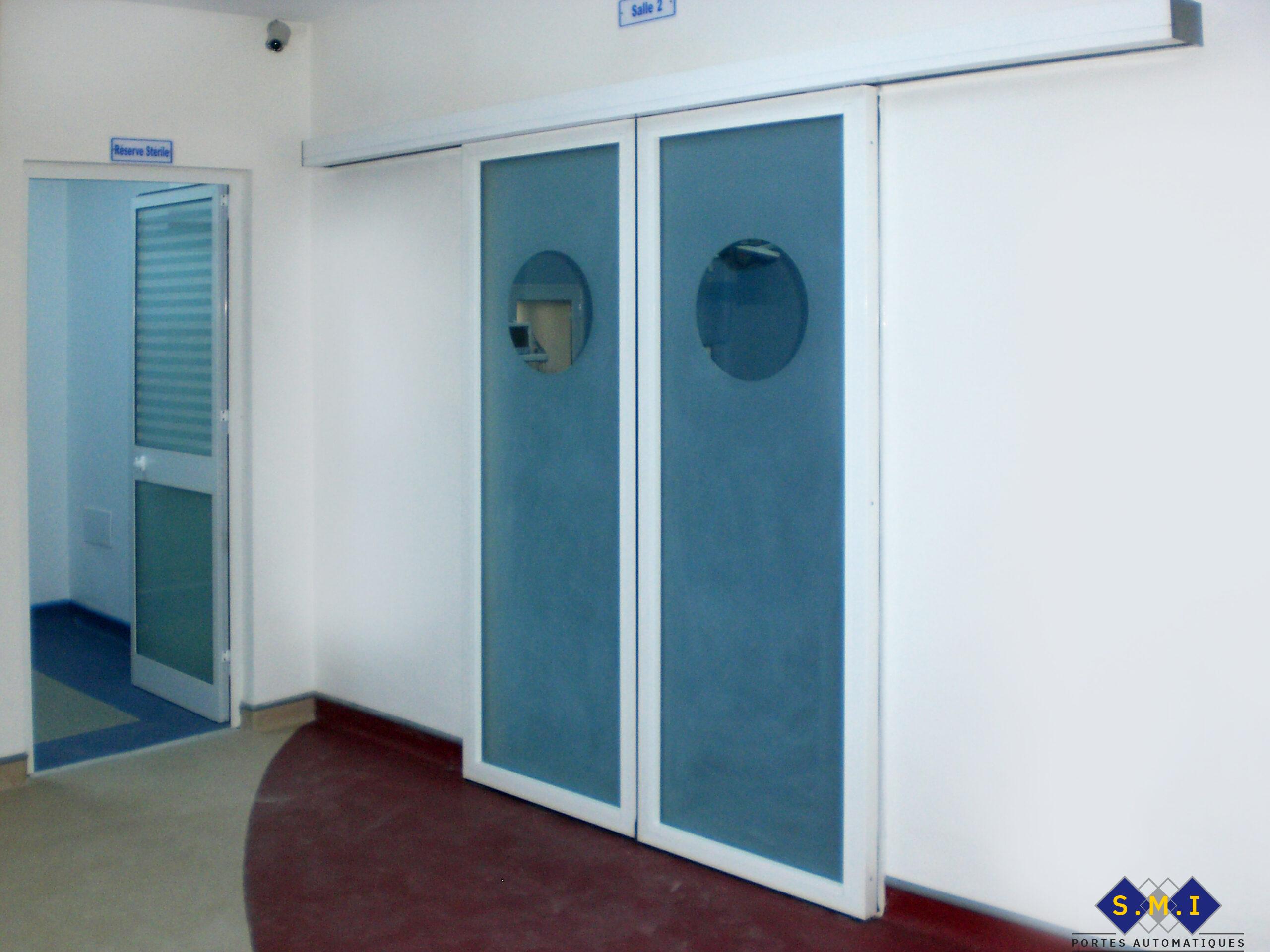 Porte radar à deux vantaux coulissants, verre sablé avec hublots claires adaptée au milieu hospitalier. Porte radar à deux vantaux coulissants, verre sablé avec hublots claires adaptée au milieu hospitalier.