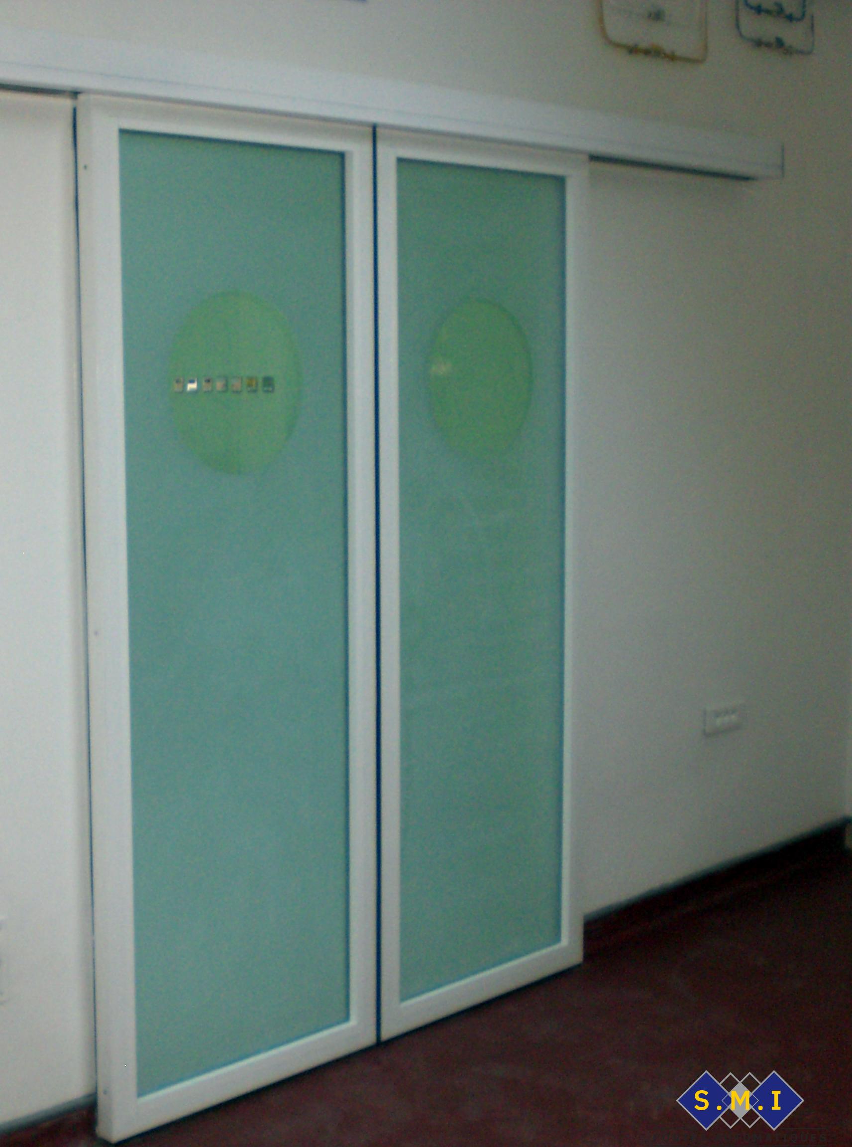 Porte radar à deux vantaux coulissants, verre sablé avec hublots claires adaptée au milieu hospitalier. Porte radar à deux vantaux coulissants, verre sablé avec hublots claires adaptée au milieu hospitalier.